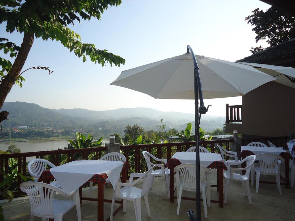 a patio with white tables and chairs and an umbrella at เชียงของฮิลล์ รีสอร์ท 