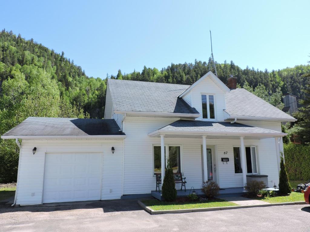 a white house with a garage at Maison d'Imelda in Petit-Saguenay