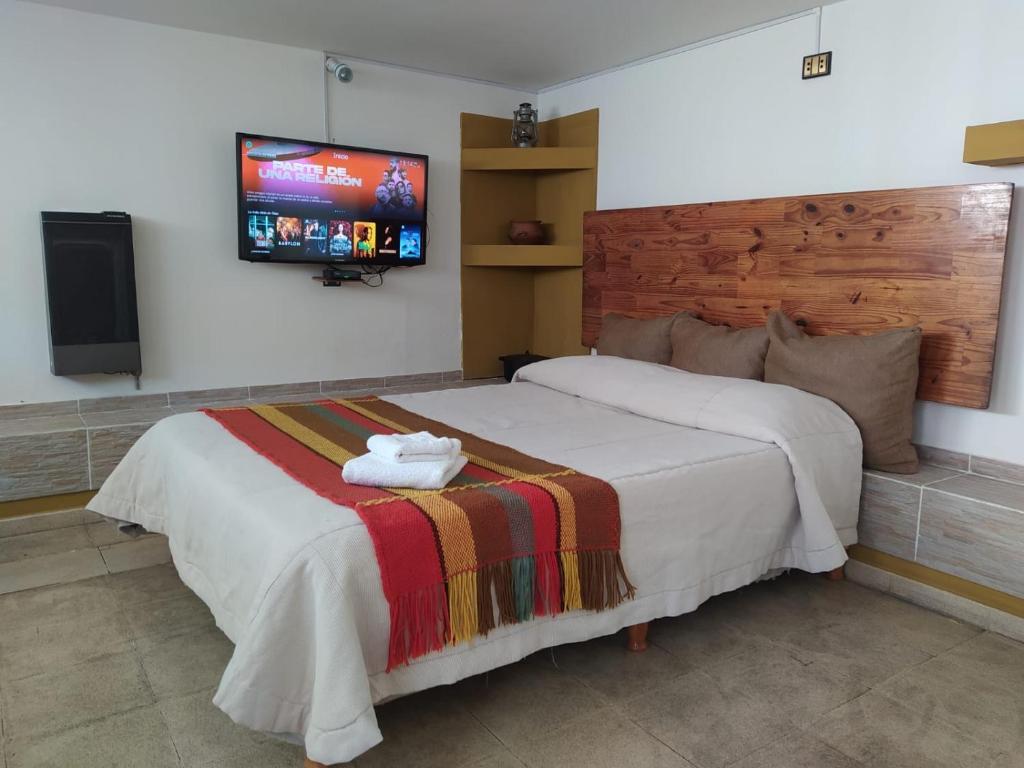 - une chambre avec un lit et une télévision murale dans l'établissement Casa Pampa, à Alta Gracia