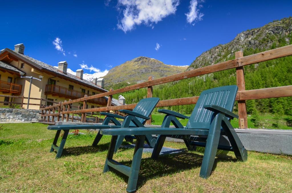 two blue chairs sitting in the grass in front of a fence at Appartamenti Residenza Anderbatt in Gressoney-la-Trinité