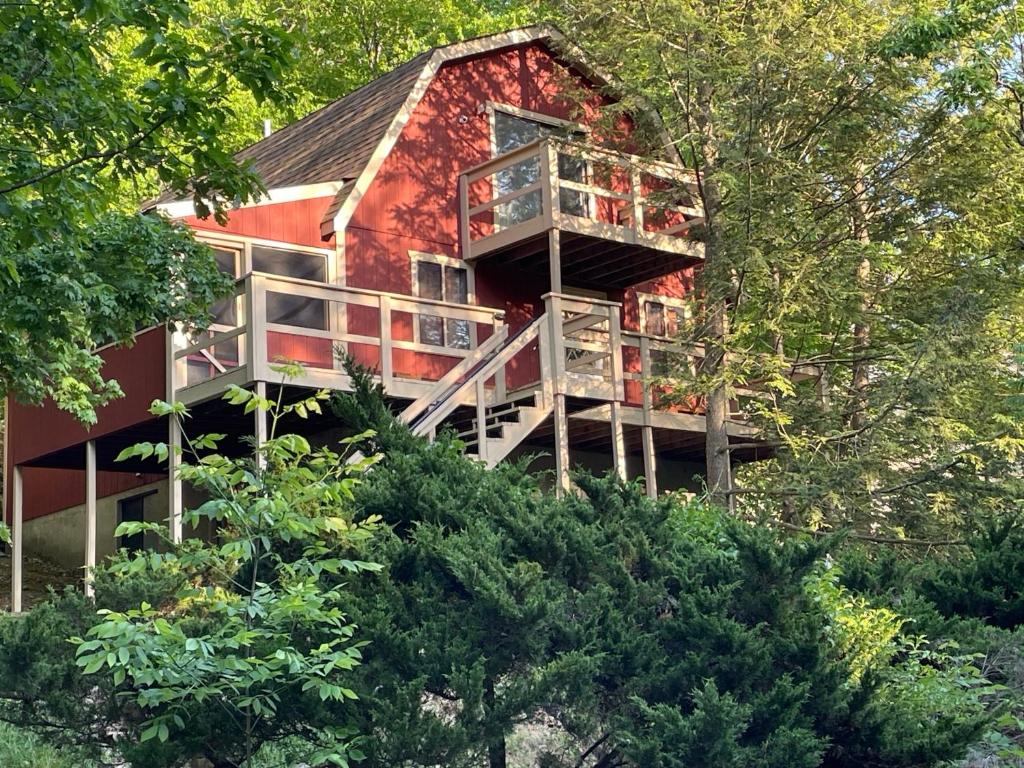 a red house on top of a hill with trees at Saw Creek Cabin - Regent Hilltop in Bushkill