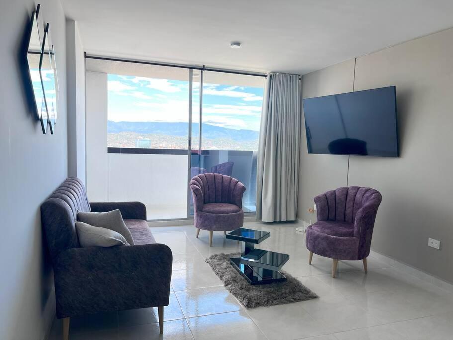 sala de estar con 2 sillas y TV de pantalla plana en Encanto urbano con la mejor vista y ubicación !, en Cúcuta