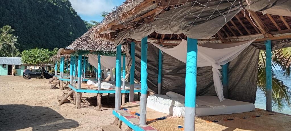 un grupo de camas en una playa con una cabaña de paja en Jaymy Beach Fales, en Apia