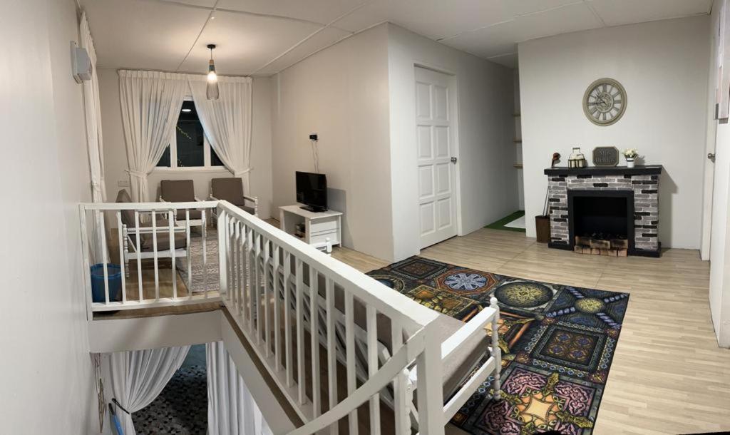 ein Zimmer mit einer Treppe und ein Wohnzimmer mit einem Kamin in der Unterkunft Qloud Cottage in Ranau