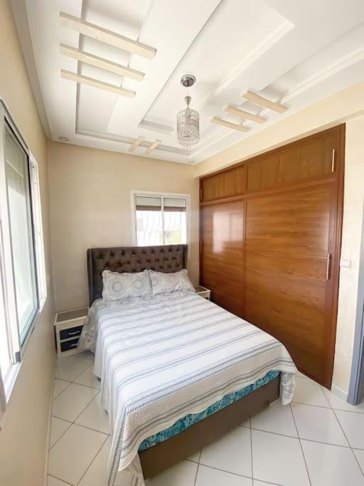 una camera con un grande letto e una porta in legno di Appartement familial 1 - Cité essalam ad Agadir