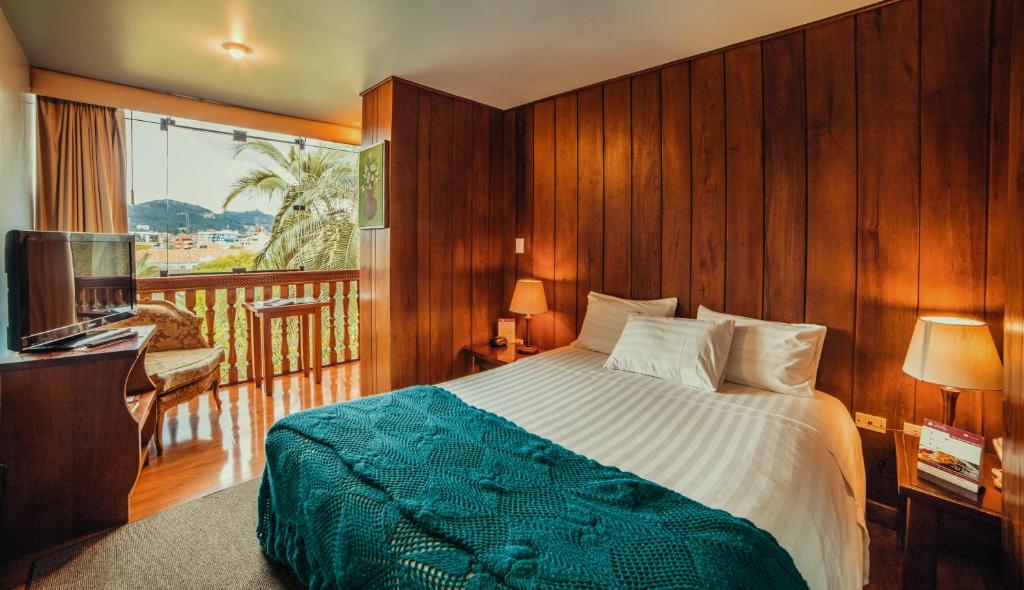 昆卡的住宿－維多利亞酒店，一间卧室设有一张床,阳台配有电视。
