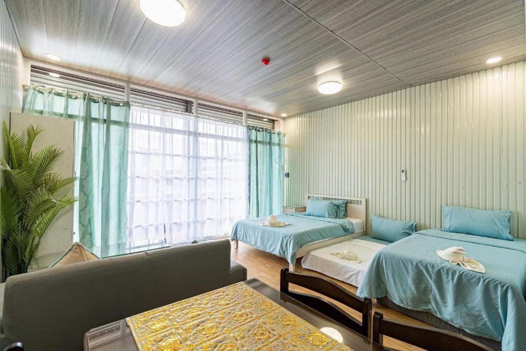 Cette chambre comprend deux lits, un canapé et une fenêtre. dans l'établissement Malaybalay Air’bnb Travellers Inn, à Malaybalay