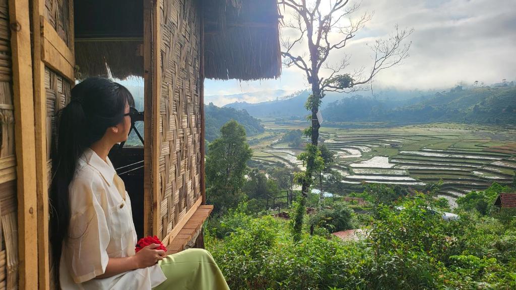 a woman sitting on a window sill looking out at a valley at KONKE RUỘNG FARMSTAY in Kon Von Kla