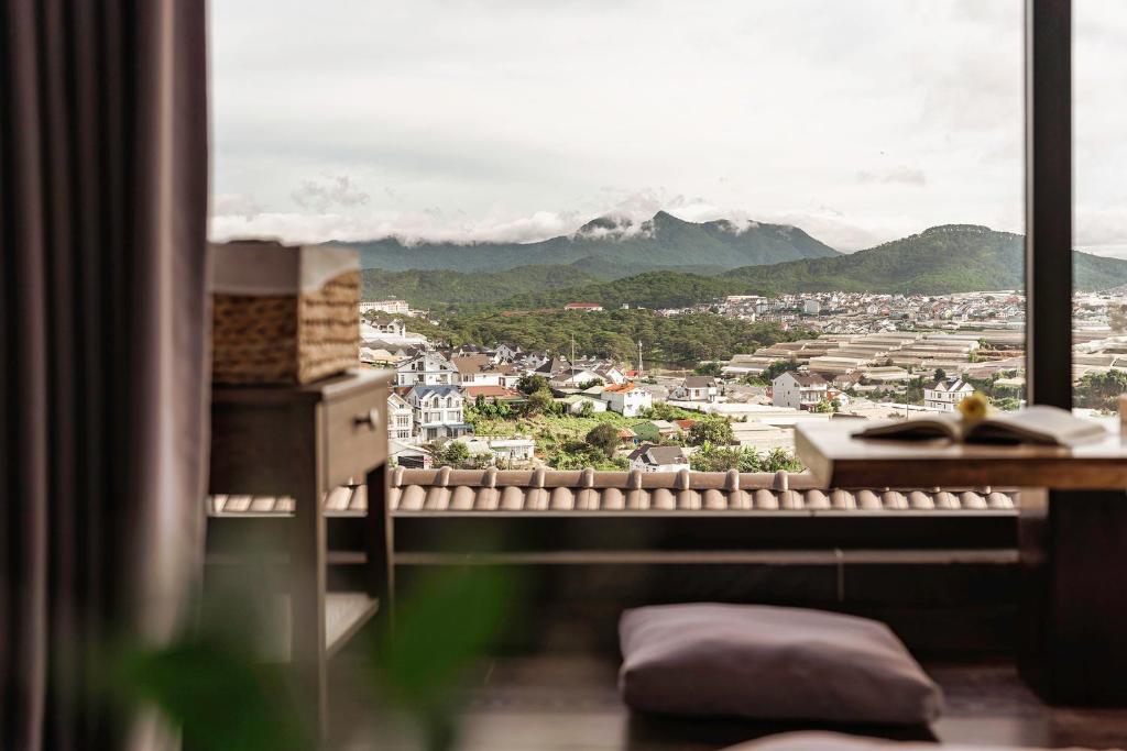 a window with a view of a city and mountains at Miền Sương Khói - Home & Café in Khu Chi Lăng