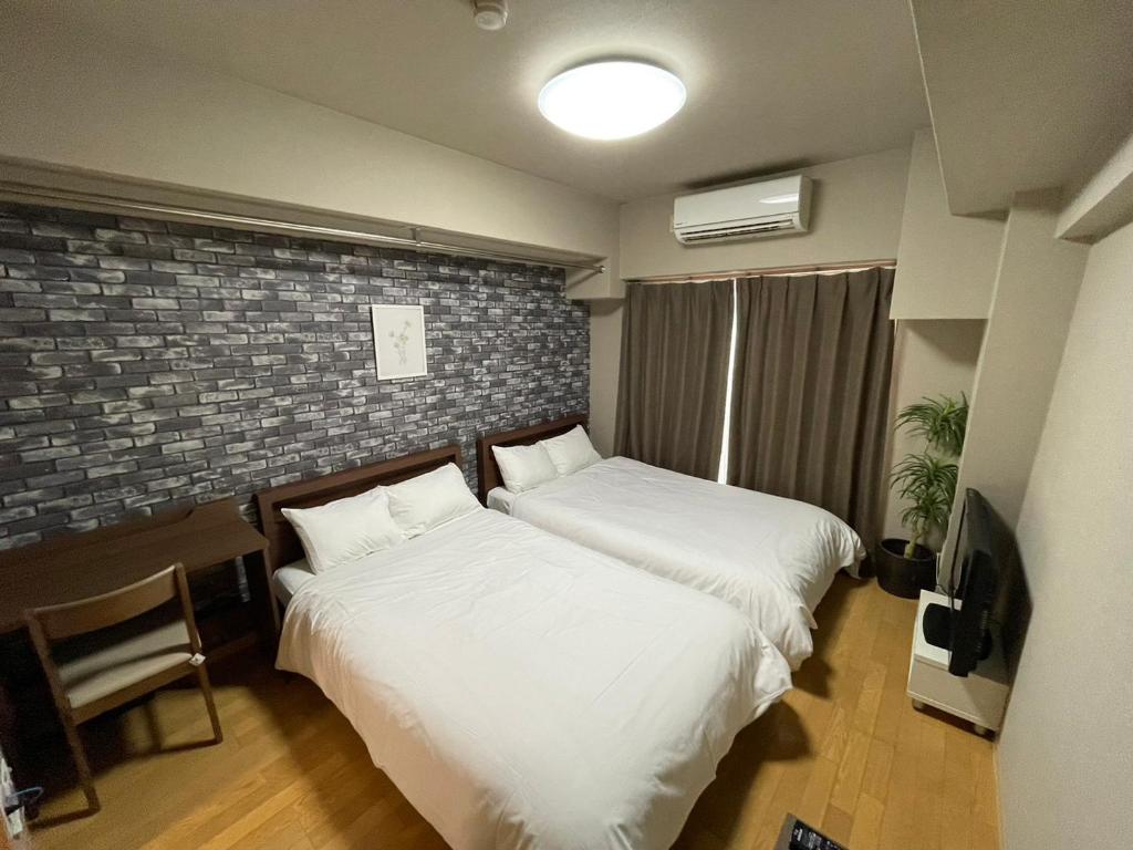 a bedroom with two beds and a brick wall at マルチステイ大阪心斎橋 in Osaka