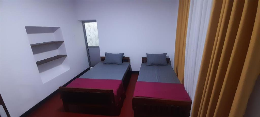 two beds in a small room with a window at Chadini Holiday Home in Gawarammana
