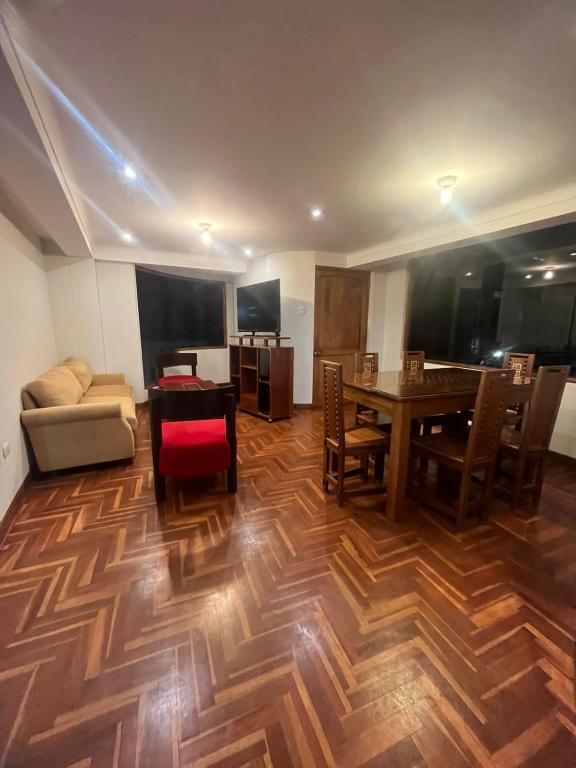 een woonkamer met een houten vloer en een tafel bij Temporary departament in Cuzco