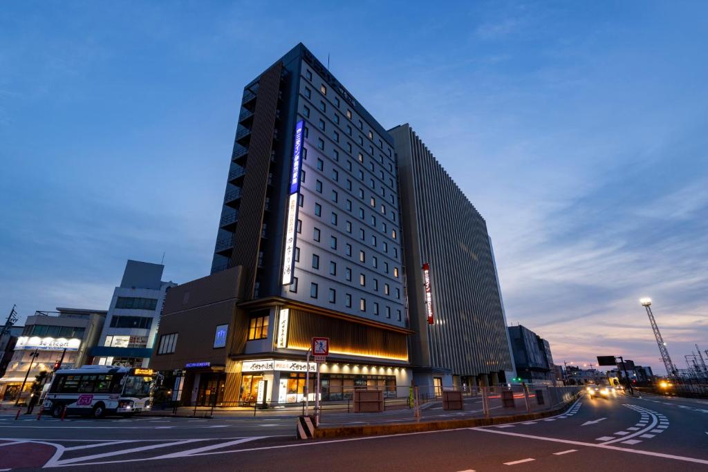 Un edificio alto en una calle de la ciudad por la noche. en Sanco Inn Iseshi-Ekimae Shikinoyu, en Ise