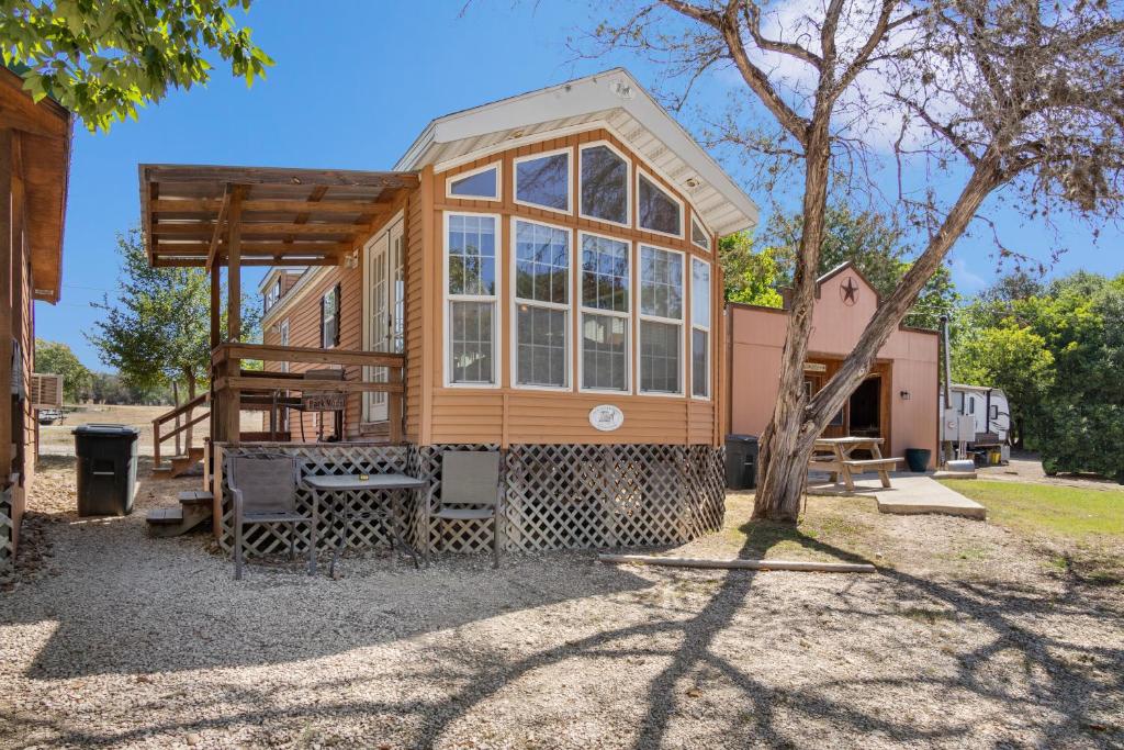 une petite maison avec une grande fenêtre et un arbre dans l'établissement River Run Park Model Cabin on Guadalupe, à Kerrville