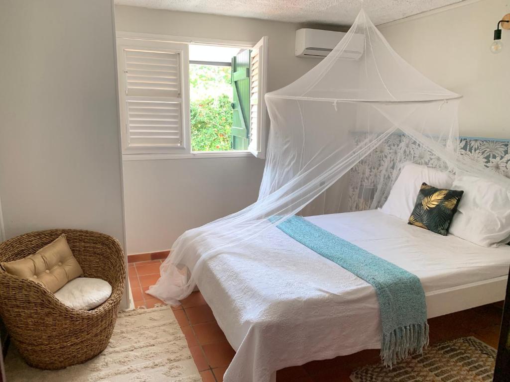 a bedroom with a canopy bed and a chair at Héritage créole 4 - Mazurka in Sainte-Luce