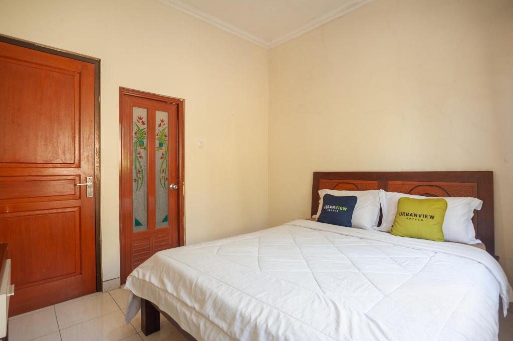1 dormitorio con 1 cama y puerta de madera en Urbanview Resort Syariah Khansa Cisarua Puncak by RedDoorz, en Tagalbato