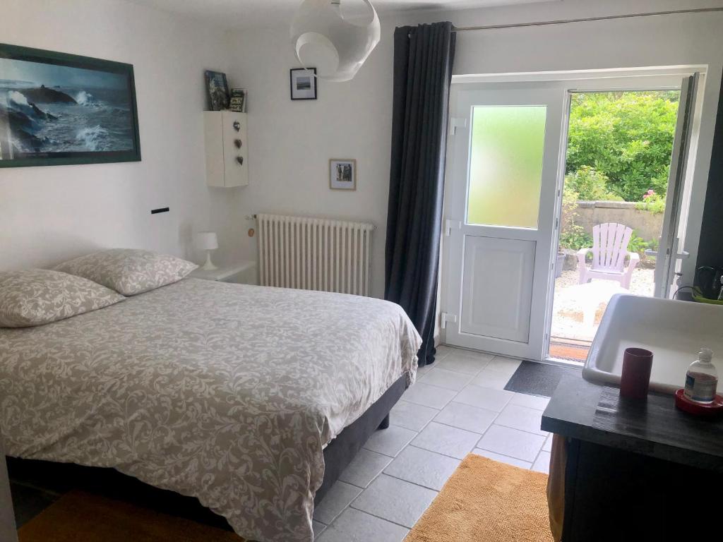 Schlafzimmer mit einem Bett und einer Tür zu einer Terrasse in der Unterkunft CHAMBRE studio POMME HAPPY Aux portes de Bayeux Normandie 1 à 2 pers in Monceaux-en-Bessin