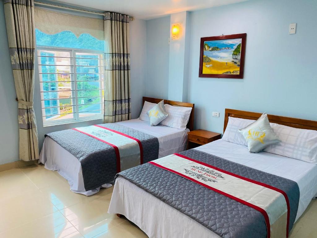 2 camas en una habitación de hotel con ventana en Nhà nghỉ Hưng Thơm en Cat Ba