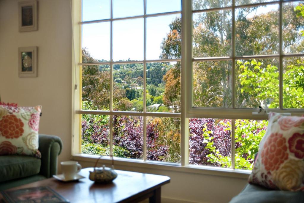 een woonkamer met een groot raam met uitzicht op een tuin bij Lake Cottage in Daylesford