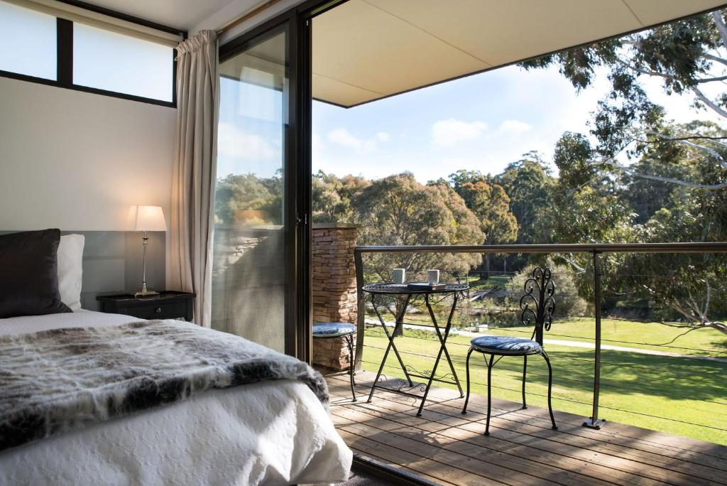 a bedroom with a bed and a balcony with a view at Lake Daylesford Lodge 6 in Daylesford