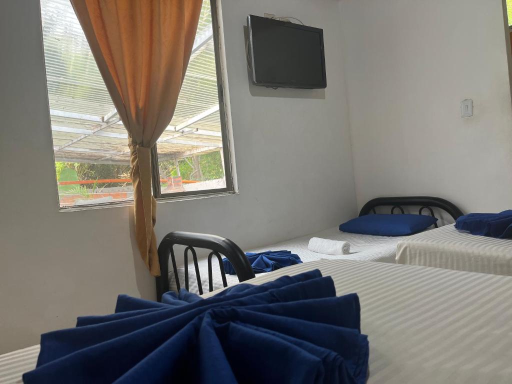 um quarto com duas camas e uma televisão e uma janela em Hotel Quinta Ana María em Melgar