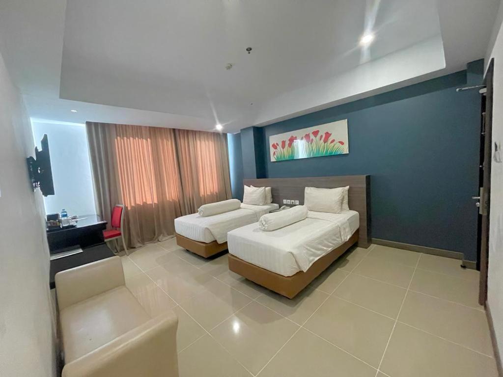 Habitación de hotel con 2 camas y sofá en Ayani Hotel Banda Aceh en Banda Aceh