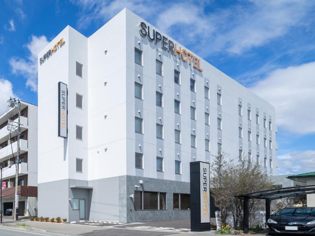 a white building with a super hotel sign on it at Super Hotel Yahaba Station East Exit in Yahaba