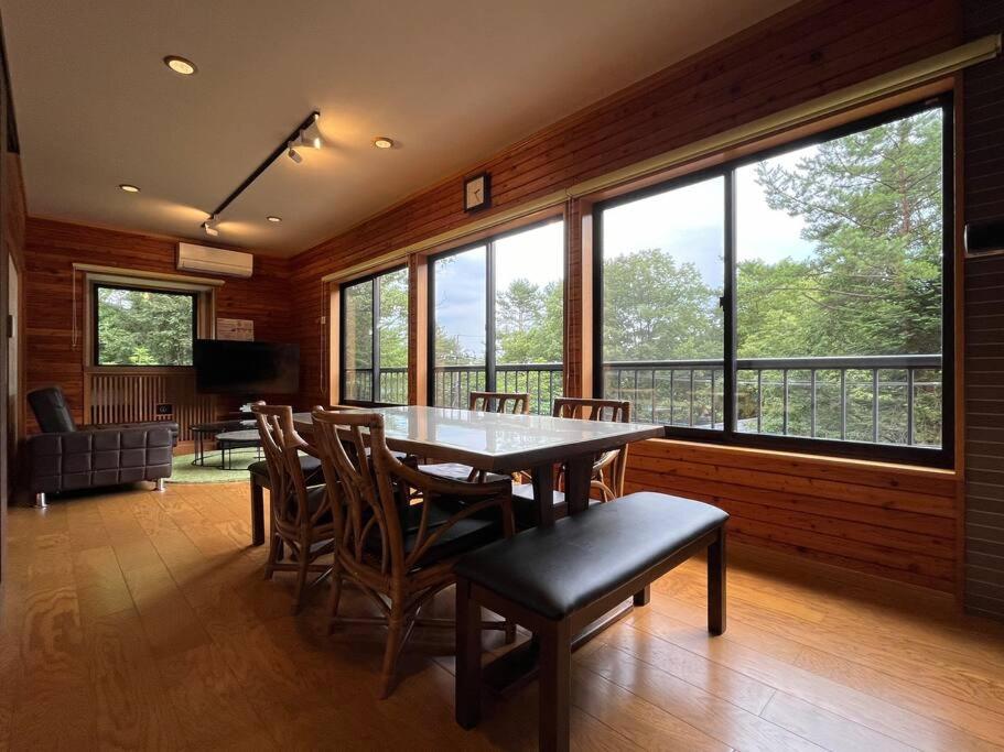 a dining room with a table and chairs and windows at FOREST HOUSE in Kusatsu