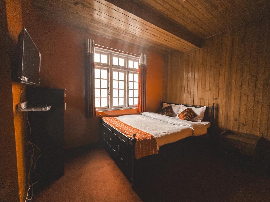 a small bedroom with a bed with a window at Mount Olive in Darjeeling