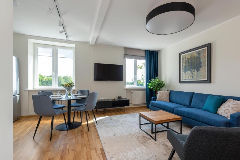 Old town luxury penthouse apartment with Emajõgi view في تارتو: غرفة معيشة مع أريكة زرقاء وطاولة