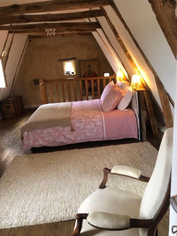 une chambre avec un lit et une chaise dans un grenier dans l'établissement La maison de César Les Eyzies de Tayac, à Sireuil