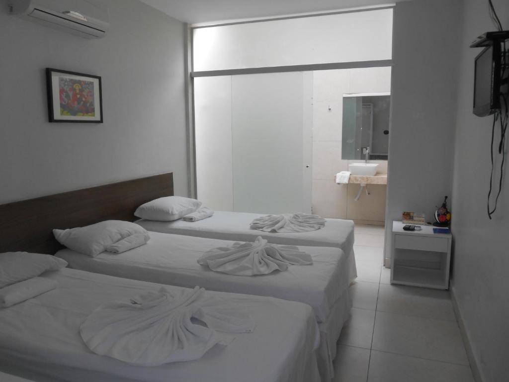 two beds in a white room with a mirror at Verde Mar Pousada in João Pessoa