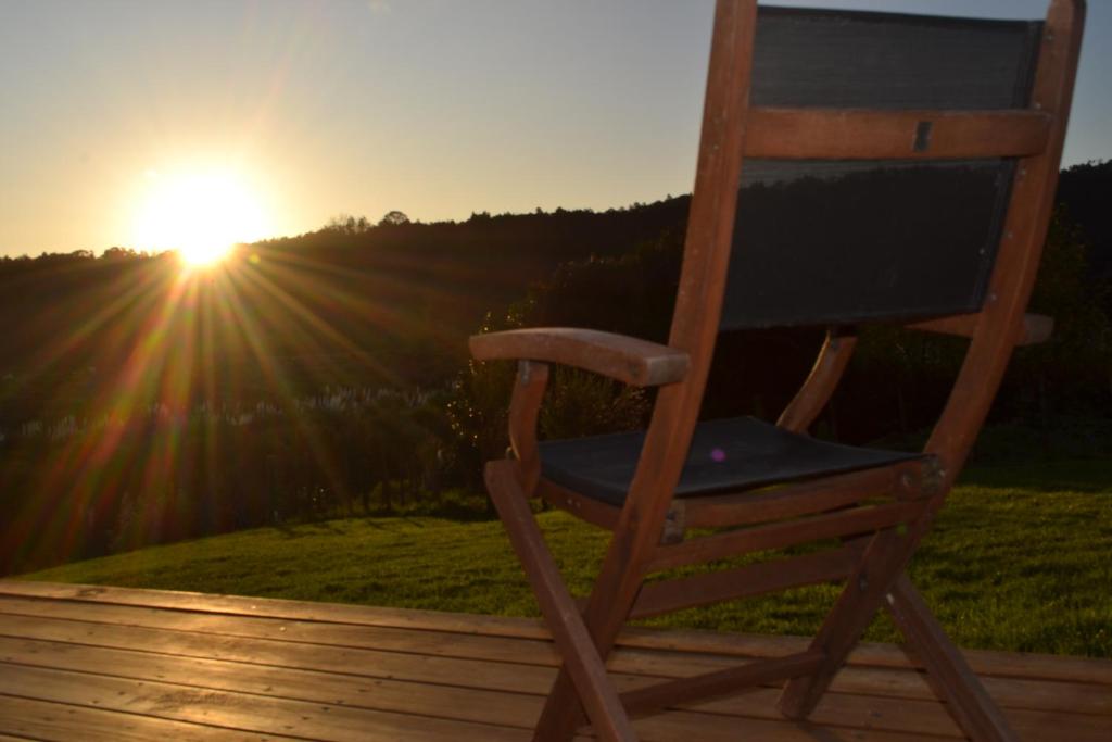 una silla de madera sentada en una terraza con vistas a la puesta de sol en Manuka Views - Close to Thermal Hot Pools, en Kaukapakapa