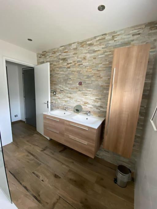 une salle de bain avec un lavabo et un mur en pierre dans l'établissement Chambre dans logement neuf et tout équipé RDC, à Felletin