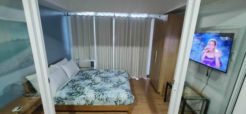 een kleine slaapkamer met een bed en een televisie bij Azure Beachview Affordable Price in Manilla