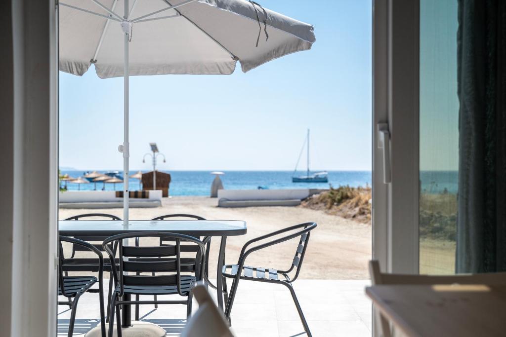 een tafel met stoelen en een parasol op het strand bij Thalassa Beach House in Kefalos