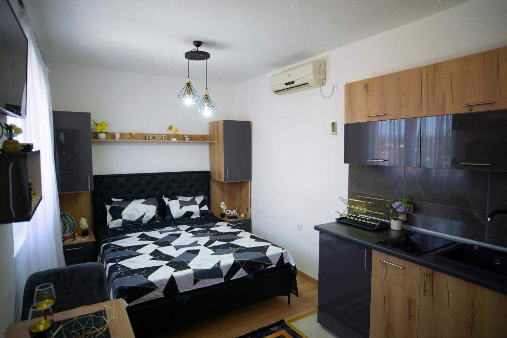 a bedroom with a black and white bed and a kitchen at Luxury Apartment Milićević 2 in Trebinje
