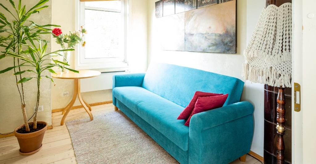 un sofá azul con una almohada roja en la sala de estar en Artists Apartment near Telliskivi Creative Centre, en Tallin