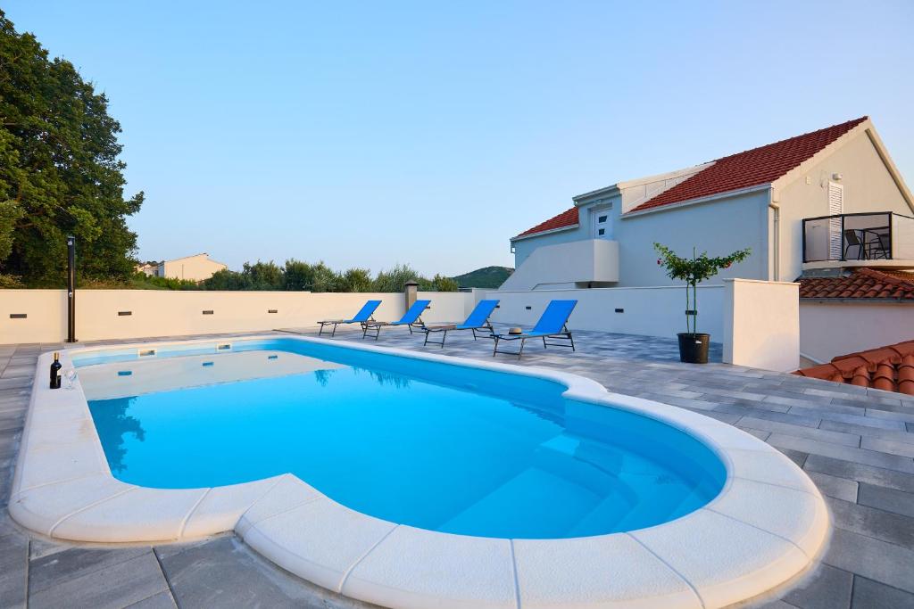 una gran piscina con sillas azules alrededor. en Mia Maria Apartment, en Cavtat