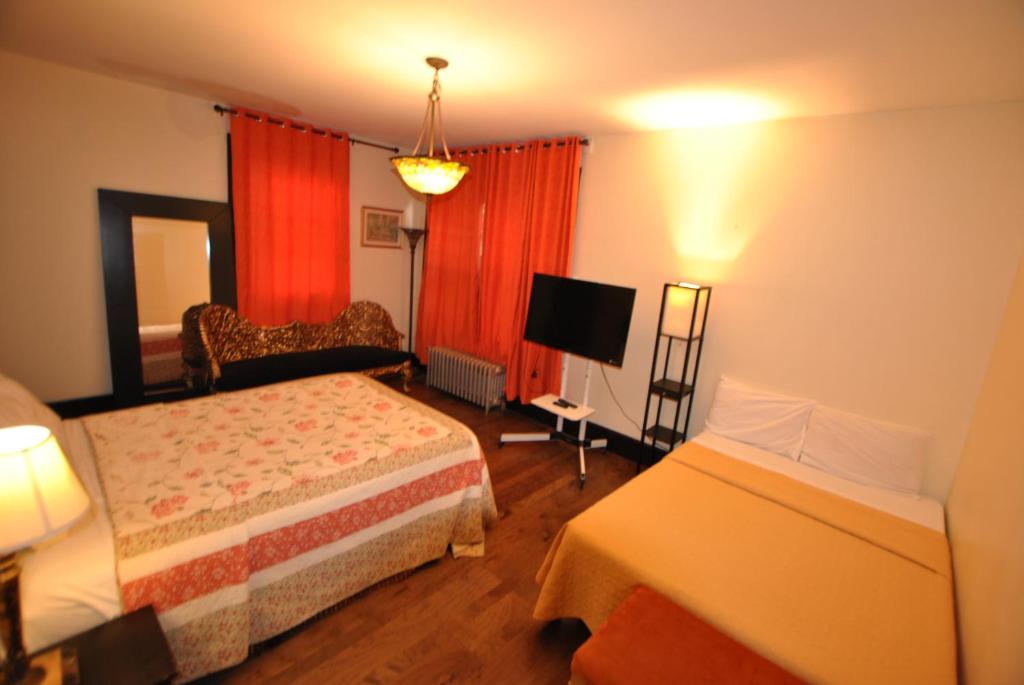 Cette chambre comprend deux lits et une télévision. dans l'établissement EWR AIRPORT Multilevel Guest House Room with 2-3 Beds, à Newark