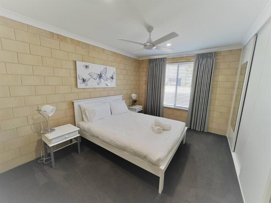 a bedroom with a large white bed and a window at Sea Stays Esperance in Esperance