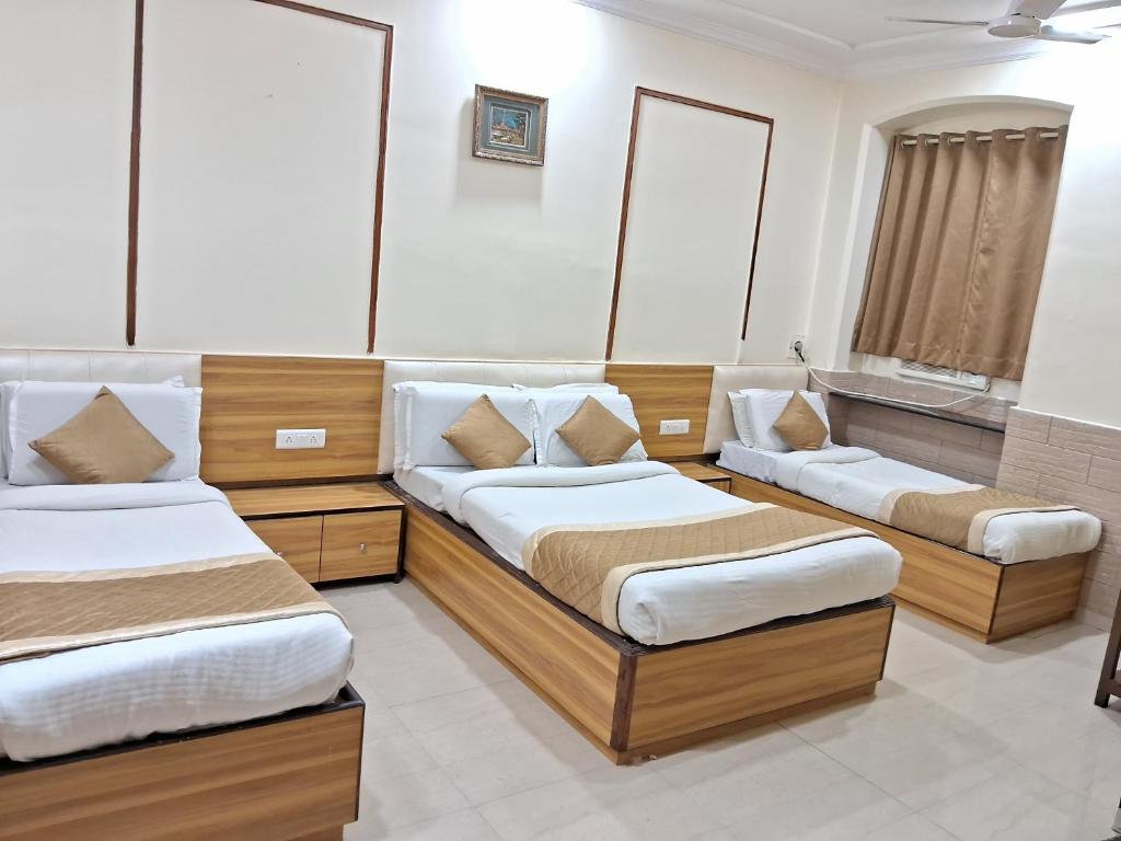 a room with three beds and a tub at Swapna International in Mumbai