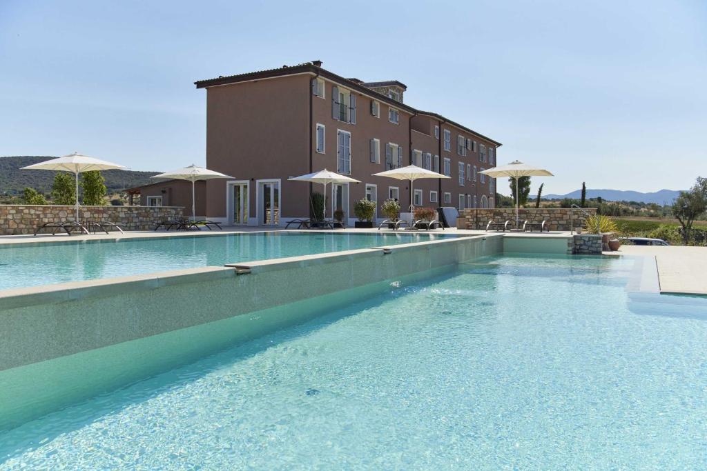 una piscina con acqua blu di fronte a un edificio di Riva Toscana Golf Resort & SPA a Follonica