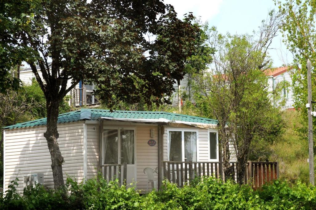 une petite maison blanche avec un arbre et des buissons dans l'établissement Camping Humawaka, à Comps-sur-Artuby