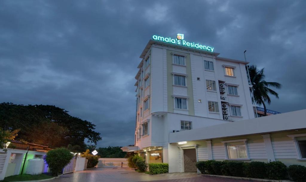 a white hotel with a sign on top of it at Amala's Residency in Trivandrum