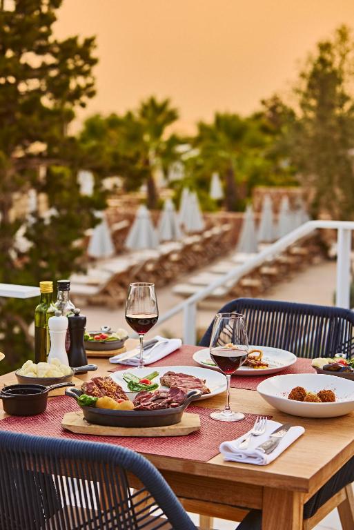 a wooden table with plates of food and wine glasses at The Signature Level at TRS Ibiza Hotel - All Inclusive Adults Only - Entrance to Clubs included in San Antonio
