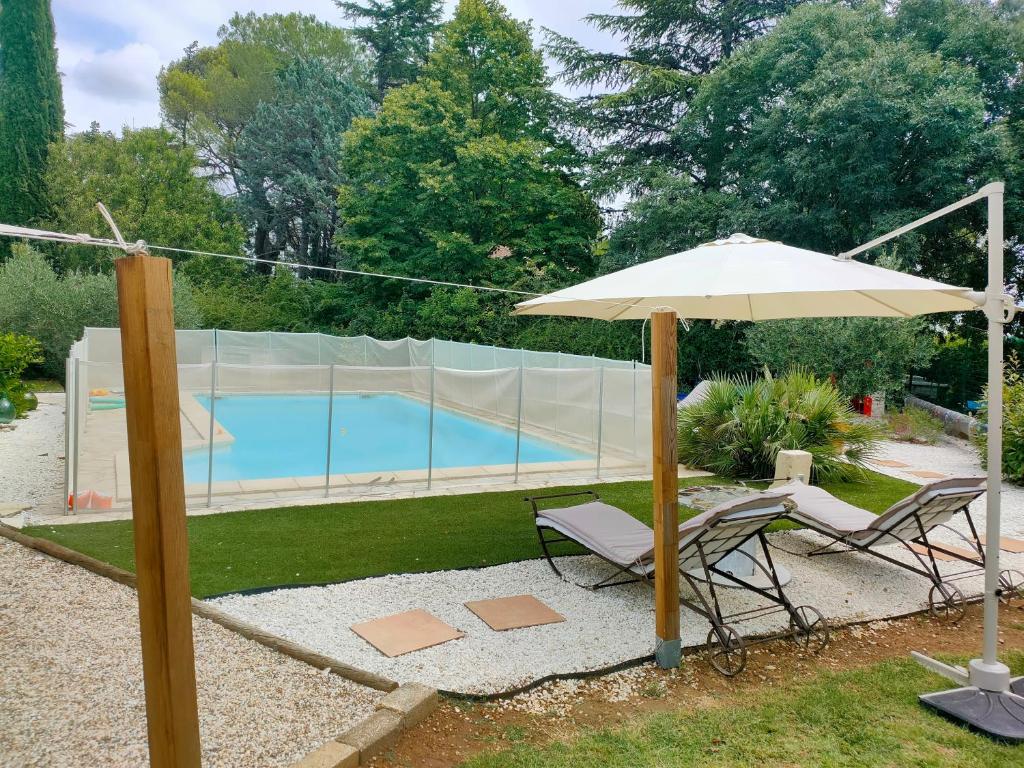 una sombrilla y dos sillas y una piscina en Au Mazet du Parc, en Lédenon