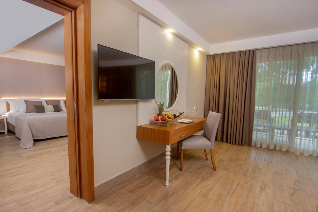 a hotel room with a desk and a television on a wall at Sherwood Exclusive Kemer - Kids Concept in Kemer