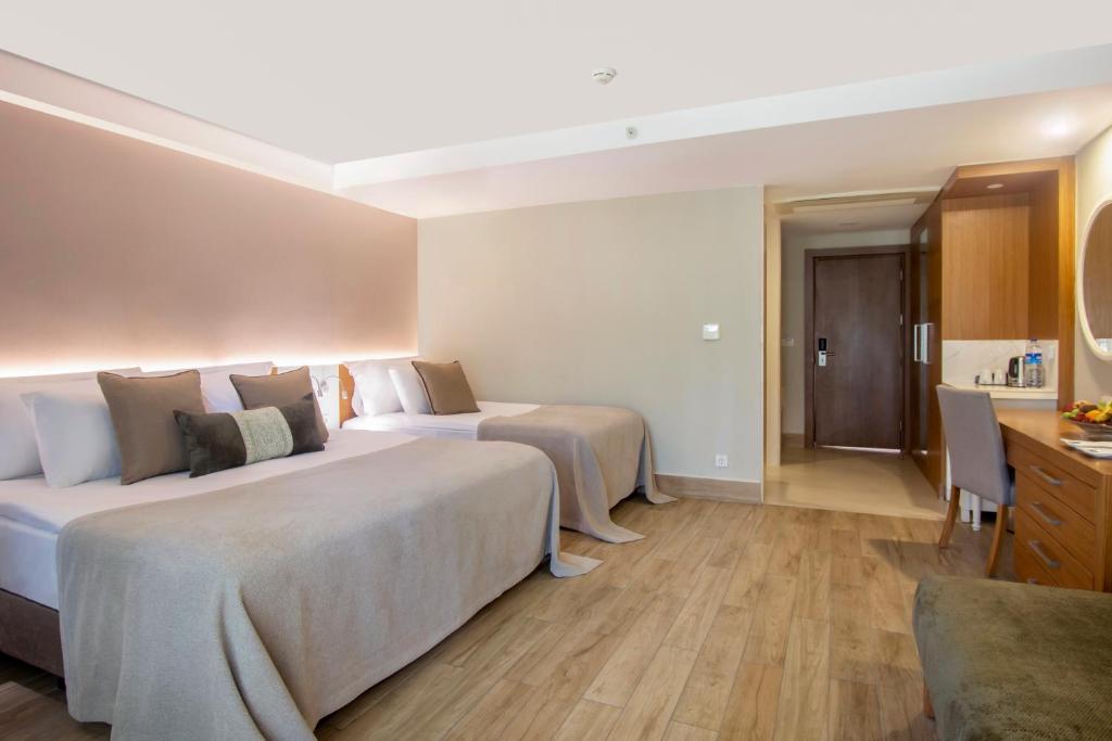 a hotel room with two beds and a desk at Sherwood Exclusive Kemer - Kids Concept in Kemer