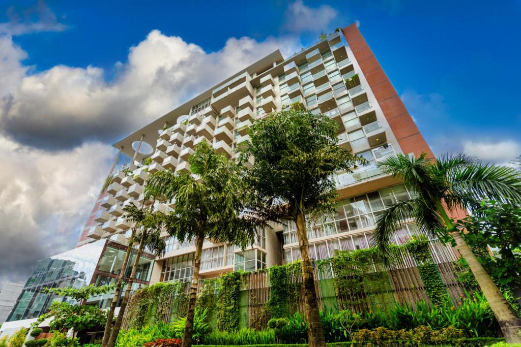 a tall building with palm trees in front of it at Best Western Heritage in Cox's Bazar